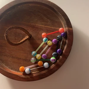 Tungpiercingar - Säljer ett gäng coola piercingstavar i olika färger som lila, orange, blå, gul, svart och vit. Kulorna har randigt mönster och vissa har även prickar. Perfekt för dig som vill ha något unikt och lekfullt till din piercing. Materialet är plast och vissa metall. SJÄLVKLART OANVÄNDA 