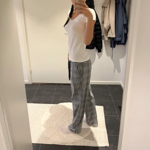 Grå-rutiga mjukisbyxor med snöre - Säljer ett par grå och vita rutiga mjukisbyxor med snörning i midjan. Byxorna har en loose passform och är perfekta för chill dagar hemma. Mjukt material och bekväm midja gör dem till ett måste i garderoben😉