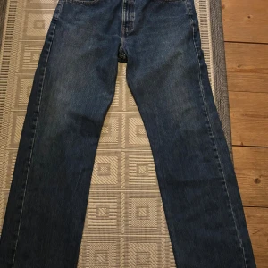 Levi's 751 raka blå jeans W33 L32 - Klassiska blå jeans från Levi's modell 751 med raka ben och normal passform. Jeansen har fem fickor, gylf med dragkedja och är tillverkade i slitstarkt denimtyg. Perfekta för dig som gillar en tidlös och avslappnad stil.