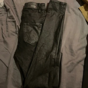 Svarta skinny jeans från Bubbelroom - Snygga svarta skinny jeans från Bubbelroom med klassisk femficksdesign och smal passform. Jeansen har en lätt glansig yta som ger en cool look och passar perfekt till sneakers eller boots. Materialet är stretchigt för extra komfort.