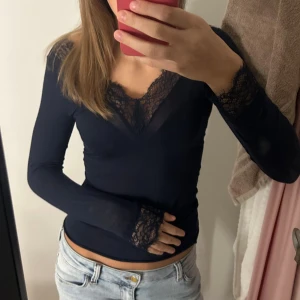 Mörkblå spets intimissimi spets tröja  - Säljer en mörkblå kashmir intimissi långärmad blus med v-ringad hals och snygga spetsdetaljer vid halsringning och ärmslut. Toppen är tight och har en feminin look som lyfter din outfit. Perfekt att styla med jeans eller kjol för en cool vibe. Varm och perfekt att ha under tröjor på vintern! 
