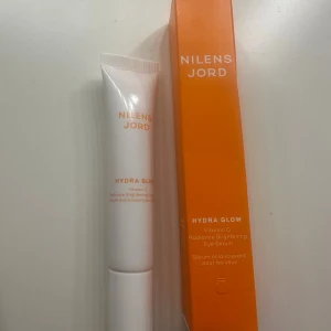 Nilens Jord Hydra Glow Eye Serum - Hydra Glow Vitamin C Radiance Brightening Eye Serum från Nilens Jord. Kommer i en vit tub med orange text och tillhörande orange kartong. Perfekt för att ljusa upp och återfukta området under ögonen.
