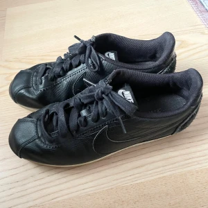 Nike Cortez svarta sneakers i skinn - Svarta Nike Cortez sneakers köpta second hand i väldigt fint skick, oanvända av mig då de inte passar 🩷 Storlek 41, normala i storleken. Skriv vid fler frågor eller funderingar!!