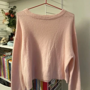 Ljusrosa stickad tröja från 157 - Mysig ljusrosa stickad tröja från 157 med rund hals och långärmad passform. Tröjan har en enkel design utan mönster och är tillverkad i ett mjukt material som känns skönt mot huden. Perfekt för dig som gillar en chill och clean look.