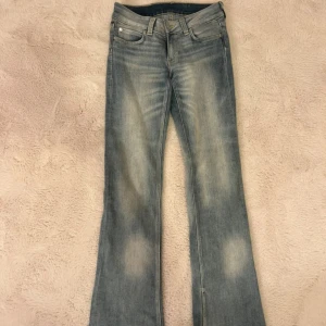 Ljusblå cheap monday jeans - Snygga bootcut jeans i ljusblå denim med slitningar och klassisk femficksdesign. Jeansen har låg midja och en lätt utsvängd passform nertill, perfekt för en avslappnad och trendig look. Små i storlek