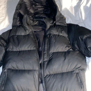 Svart pufferjacka från Polo Ralph Laurent - Säljer en fet jacka till vintern från polo Ralph Laurent.Jackan är svart och har ett svart polo märke på bröstet.Ny pris 6000kr och jackan säljs inte längre.hör av er om frågor,pris kan diskuteras.