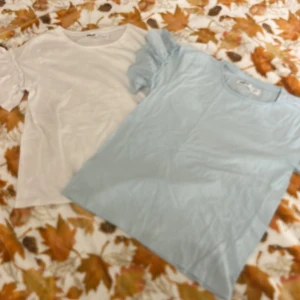 Ljusblå Minoti t-shirt med puffärm - Säljer två ljusblåa t-shirt från Minoti i mjuk bomull. T-shirten har korta puffärmar med rynkade detaljer som ger en söt och trendig look. Perfekt för dig som gillar en enkel men ändå stylish vibe.