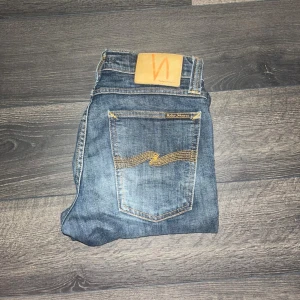 Nudie Jeans - Säljer ett par klassiska blå jeans från Nudie Jeans med snygg fade. Modell Tube Kelly. Midja 34cm, längd 100cm. JAG SKICKAR EJ FLER BILDER NÄR JAG BÄR JEANSEN! för storleksguide hänvisar jag till måtten och för bättre inblick i passformen rekommenderar jag att googla på modellnamnet. Jeansen kan vara uppsydda utan att jag noterat det så kolla måtten noggrant :) S3