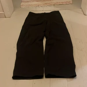 Svarta baggy byxor från H&M - Svarta baggy byxor från H&M med justerbar midja. Byxorna har raka, vida ben och klassisk knappstängning framtill. Perfekta för en avslappnad och trendig look.