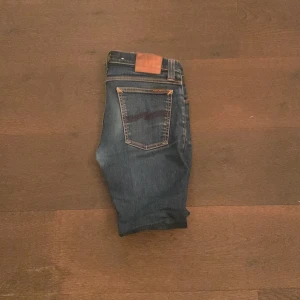  Nudie Jeans - Snygga blå jeans från Nudie Jeans med klassiska kontrastsömmar och ikonisk bakficka. Modellen har normal passform och raka ben. Tillverkade i slitstarkt jeanstyg som ger en tidlös look. Perfekta för dig som gillar stilrena och bekväma jeans.