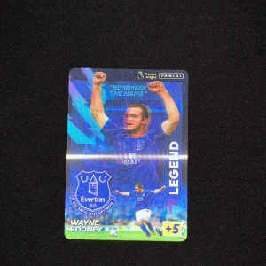 Legend - Upptäck en hyllning till fotbollsikonen Wayne Rooney! Denna Panini Premier League-samlarbild visar Rooney i Everton-tröjan, perfekt för dig som älskar sport, samlarbilder och vill ha en bit av fotbollshistorien i din samling.