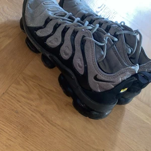 Nike Air Vapormax grå/svarta sneakers - Nike Air Vapormax sneakers i grått och svart små skador på framsidan även på insidan som inte syns och känns inte jobbig 