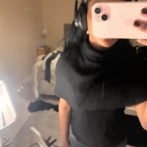 Svart stickad ”tröja” med polokrage - Snygg svart tröja med polokrage, stickad i mjukt material. Modellen är bred och ligger snyggt över axlarna, perfekt för att ge extra värme och stil till din outfit.