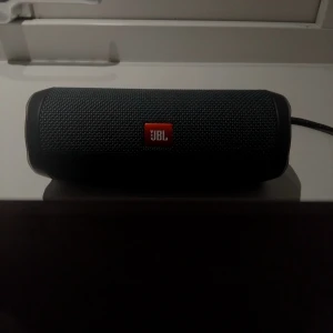 JBL Essential Flip 2 - JBL Essential Flip 2 är en portabel Bluetooth-högtalare med kraftfullt ljud och robust design. Den är vattentålig, har lång batteritid och tydliga knappar för enkel användning. Högtalaren är i mycket gott skick utan skador 