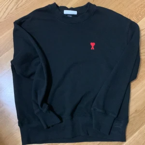 Svart sweatshirt från Ami med rött hjärta - Snygg ami Paris tröja med rött hjärta som säljs för att den inte används längre. Den är väldigt bra för alla årstider förutom sommar. Vid snabb affär får du ett bra pris