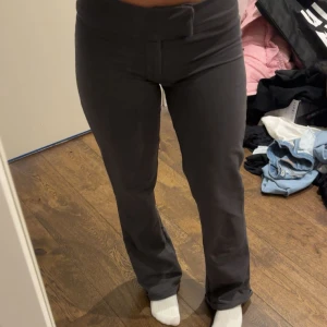 Mörkgrå bootcut byxor - Snygga mörkgrå bootcut byxor med låg-mid midja och smickrande passform. Byxorna har en enkel design utan synliga detaljer och är tillverkade i ett mjukt material som ger en bekväm känsla. Perfekta för dig som gillar stilrena och trendiga plagg.