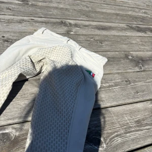 Beiga ridbyxor från Equiline - Snygga beiga ridbyxor från Equiline med helskodd silikongrepp och broderad logga på benet. Byxorna har normal passform, bälteshällor och är tillverkade i ett stretchigt material som ger bra rörelsefrihet när du rider.