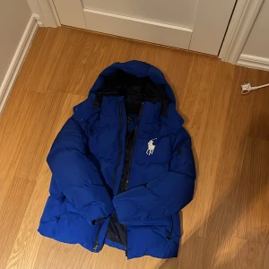 Blå pufferjacka från Polo Ralph Lauren - Snygg blå pufferjacka från Polo Ralph Lauren, ny pris är runt 4000 kr passar dig som är mellan 155-175 ish. Säljer för att den är för liten och för ett bra pris 🏷️🤑👍 