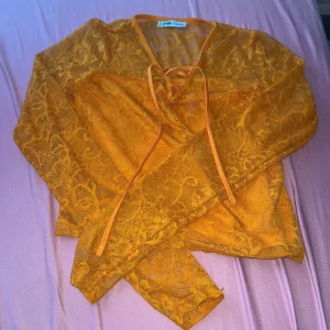 Gul spetsblus med snörning - Säljer en snygg gul blus från PrettyLittleThing i transparent spets med långa ärmar och v-ringning. Toppen har snörning framtill och är croppad. Perfekt för dig som vill sticka ut med färg och coola detaljer.