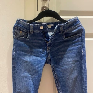 Blå jeans från Gina Tricot, storlek 170 - Snygga blå jeans från Gina Tricot med klassisk femficksdesign och kontrastsömmar. Modellen har normal passform och dragkedja med knapp framtill. 