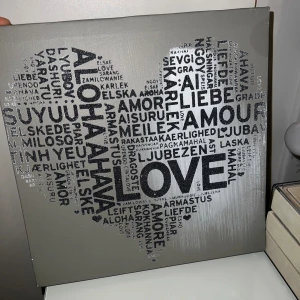 LOVE (konsttryck) 30”30 - Stilren tavla med ordet 'LOVE' och dess översättningar på många olika språk, formad som ett hjärta. Perfekt för att ge ditt rum en modern och internationell känsla. Passar dig som gillar minimalistisk konst och vill sprida kärlek i din inredning.