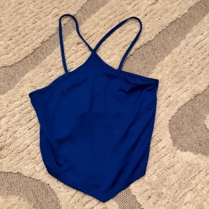 Blå bikiniöverdel från Gina Tricot - Snygg blå topp från Gina Tricot i storlek M. Modellen har smala axelband och en enkel, stilren design utan mönster eller detaljer. Materialet är mjukt och stretchigt, perfekt för varma sommardagar. 