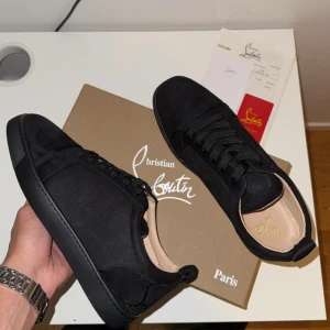 Christian Louboutin Sneakers - SwedenFashionOutlet säljer nu exklusiva Christian Louboutin sneakers i svart mocka, storlek 43, med den ikoniska röda sulan. Skorna är i nyskick och kommer komplett med kartong och tillbehör (se bild). Priset är endast 1349 kr. Vi erbjuder jättesnabb frakt! Dessa är mycket populära, så det är först till kvarn som gäller. Skicka ett meddelande direkt för att köpa dem! 
