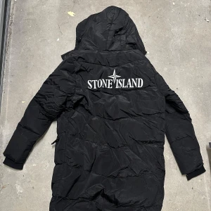 Svart lång dunjacka Stone Island - Svart lång dunjacka från Stone Island, perfekt inför vintern! Storlek: S
