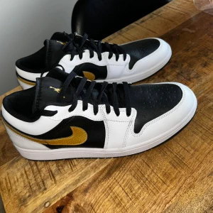 Nike Air Jordan 1 Low svart/vit/guld - Hej jag säljer mina helt nya Air Jordan 1 Low "Gold Swoosh. Köpta från Nike butiken i Barkarby. Tyvär var dom inte riktigt min still men kanske passar bättre hos någon annan