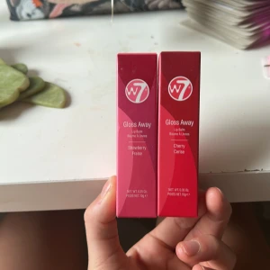 W7 Gloss Away Lip Balm duo - Två Gloss Away Lip Balm från W7, en med jordgubbssmak i rosa förpackning och en med körsbärssmak i röd förpackning. Båda är veganska och PETA-godkända, innehåller 10g vardera och har en snygg, modern design.