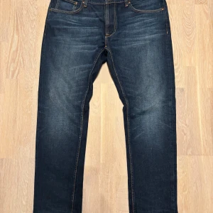 Mörkblåa Nudie jeans, stolek w38 - As feta nudie jeans med en orolig tvätt och slitningar, sparsamt använda finns knappa tecken på användning! Storlek W38. Funderingar på mått eller liknande så är det bara att höra av sig!