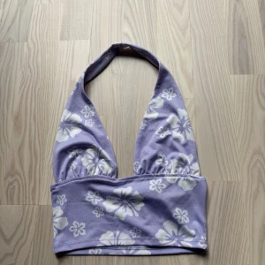Lila blommig halterneck top från hm - Superfin halterneck tio i lila från HM Divided med stora vita blommor. Halterneck-modell med bred resår under bysten och djup urringning. Skick är jätte svårt att sätta då alla tycker olika, men jag tycker att det är ett mycket bra skick på toppen 