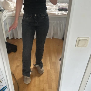Svarta jeans - Säljer ett par svarta jeans med klassiska  raka ben. Jeansen har hög midja, slitna benslut för en cool och avslappnad vibe. Tillverkade i denim som ger en snygg passform och vintagekänsla.