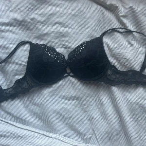Svart spets-bh från Victoria's Secret - Säljer en svart bh från Victoria's Secret med vacker spets och små glittriga stenar på kuporna i storlek 34B. Bh:n har justerbara axelband och en feminin design med fina spetsdetaljer. 🩷bilden längst bak är inte exakt samma bh som denna, men det är ett ungefärligt utgångspris🫶🏼🫶🏼