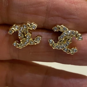  örhängen med strass och guld -  örhängen i guldtonad metall med gnistrande strass-stenar.  i en cool, tvinnad design som verkligen sticker ut. Perfekta för dig som vill ha en lyxig och trendig accessoar med extra bling.