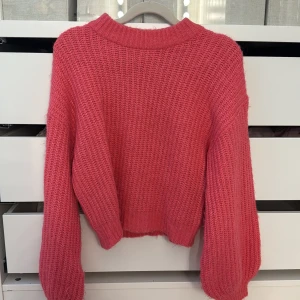 Rosa stickad tröja från Vila - Supermysig rosa stickad tröja från Vila i storlek S. Tröjan har en chunky ribbstickad struktur, rund halsringning och långa ärmar med breda muddar. Perfekt för att hålla sig varm och snygg under kyliga dagar. Använd fåtal gånger så den är som ny!