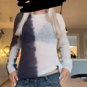 Stickad tvåfärgad tröja i svart och vit - Säljer en stickad tröja med coolt tvåfärgat mönster i svart och vit. Tröjan har lång ärm och rund halsringning, perfekt för dig som gillar en unik och trendig stil. Materialet är mjukt och skönt, passar perfekt till jeans.