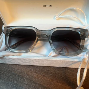 Gråa CHIMI solglasögon fyrkantig modell - Snygga solglasögon från CHIMI i transparent grå färg med fyrkantig form. Modellen är 04 Grey och har mörka linser. Ramen är robust och stilren, perfekt för dig som vill ha en modern och clean look. Kommer med originaletui och box. Dem är aldrig använda, skriv och fråga vid minsta undran så för du ett svar!