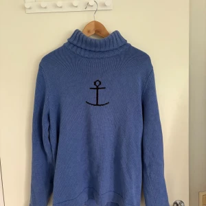 Haddock stickad tröja i M - Blå stickad polotröja / haddock tröjan från Jumperfabriken i storlek M. Tröjan har en hög, ribbad polokrage i ljusblå färg. Slutsåld på deras hemsida. Sjukt snygg 