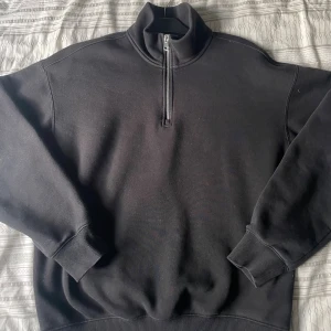 Svart half zip sweatshirt från H&M - Svart sweatshirt från H&M med loose fit och halv dragkedja framtill. Tröjan har hög krage, ribbade muddar och är tillverkad i mjuk bomullsblandning. Perfekt för chill dagar eller när du vill ha en enkel och clean look.