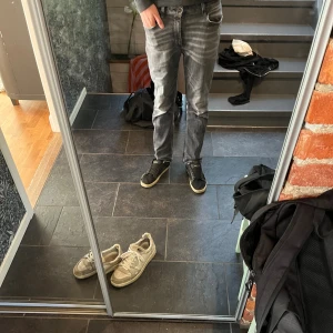 Grå slil fit jeans från Dondup, stl 29 - Säljer ett par grå slim fit jeans från Dondup med slitna detaljer och snygg tvätt. Jeansen har klassisk femficksdesign, låg midja och är tillverkade i en stretchig bomullsblandning för skön passform. Perfekta för dig som gillar en smal siluett. Säljer eftersom att jeansen är för små.