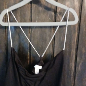 Svart från H&M XS - Svart satin line med jättefin korsning med silverglittriga band perfekt för en utekväll eller fräsch look! Storlek xs men passar mig som har m/s