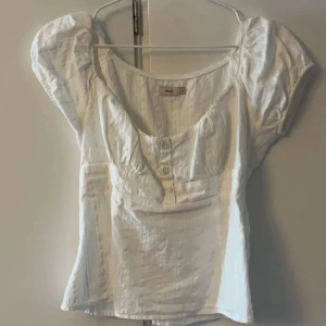 Vit blus med puffärm från Nelly - Söt vit blus från Nelly med puffiga korta ärmar och knappar framtill. 