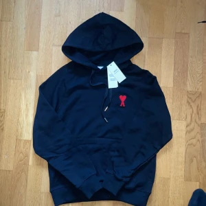 Svart hoodie från Ami med rött hjärta - Svart hoodie från Ami med huva och snörning. På tags finns kvar och perfekt tröja nu till hösten och vintern. Om du har mer frågor, eller vill ha mer bilder Skriv privat.