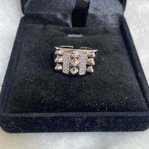  silver spike ring  - Cool bred ring i silverfärg med två rader glittrande stenar och dekorativa nitar. Ringen har en öppen baksida som gör den justerbar och ger en edgy vibe. Perfekt för dig som vill sticka ut med accessoarerna. Rostfri 