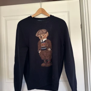 Ralph Lauren stickad tröja med björn - En ralph lauren tröja stickad i merino ull. Super skön och snygg, passar perfekt till höst o vinter vädret. Modellen på bilden är ca 175 samt väger runt 60. Storleken är S och är något mindre än vanlig S. Tröjan är endast använd inomhus ett fåtal gånger. Skick 10/10. 