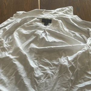 Vit skjorta från Ralph Lauren - Klassisk vit skjorta från Ralph Lauren med broderad logga på bröstet. Skjortan har lång ärm, knappar framtill och är tillverkad i mjuk bomull. Perfekt för en clean och stilren look. Säljer pga för liten (aldrig använt)