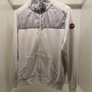 Vit och grå ziptröja från Colmar - Snygg vit ziptröja från Colmar med ljusgrå quiltad panel upptill och ribbade muddar. Hög krage, två fickor fram och dragkedja hela vägen. Perfekt för lager-på-lager och chill vardagsstil.