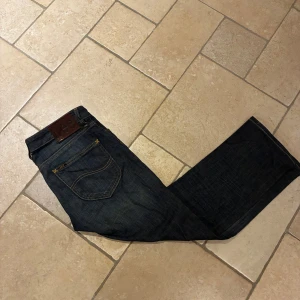 Lee Marion Straight jeans blå W28 L35 - Säljer ett par mörkblå Lee Marion Straight jeans med klassisk rak passform. Jeansen har snygga kontrastsömmar, bakficka med Lee-läderpatch och är tillverkade i bomull med lite stretch för extra komfort. Storlek W28 L35