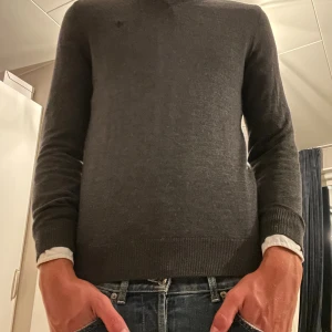 Mörkgrå merinoullströja från Morris - Snygg mörkgrå tröja från Morris i mjuk merinoull. Klassisk rund halsringning och diskret broderad logga på bröstet. Perfekt för lager-på-lager och passar till både jeans och chinos. Långärmad och med ribbade muddar för en clean look.